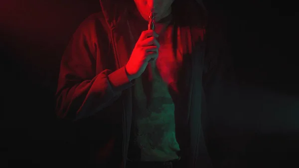 Foto do homem com vape na fumaça vermelha e verde — Fotografia de Stock