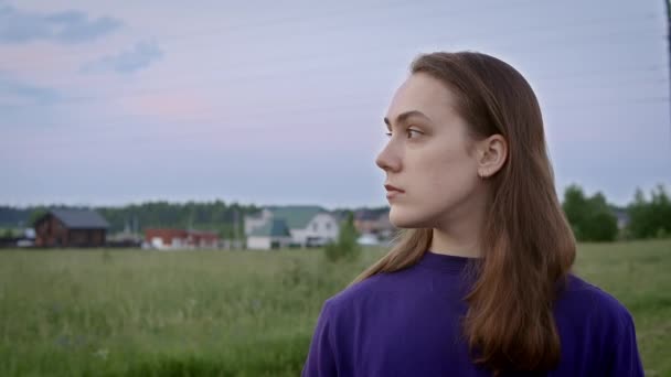 Vídeo de jovem mulher em camisa roxa no campo durante o pôr do sol — Vídeo de Stock