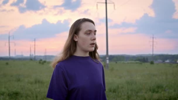 Bilder på ung kvinna i lila skjorta på landet under solnedgången — Stockvideo