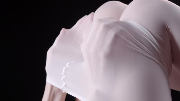 Видео женских рук под белыми колготками на черном фоне — стоковое видео