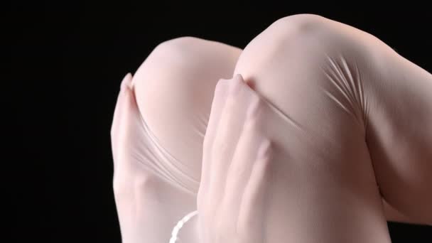 Weibliche Hände unter weißen Strumpfhosen auf schwarzem Hintergrund — Stockvideo