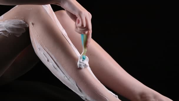 Strzelanie do kobiety golącej nogi brzytwą na czarnym tle — Wideo stockowe