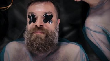 Gözlerinde siyah koli bandı olan sakallı adamın videosu.