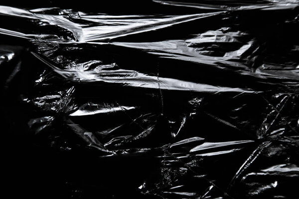 Фото полиэтиленовой поверхности с рваной дырой на черном фоне