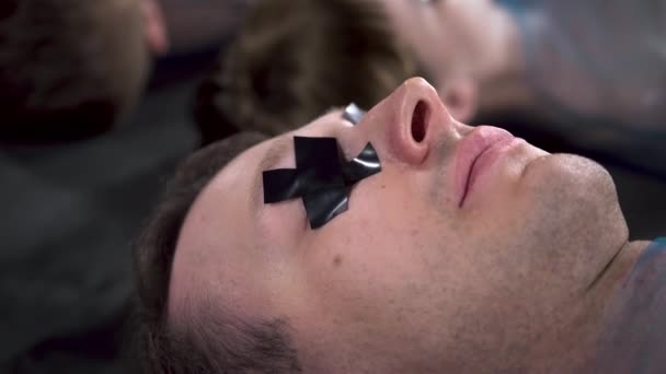 검은 색 덕트 테이프 눈을 가진 금발의 남자가 누워 있는 모습 — 비디오