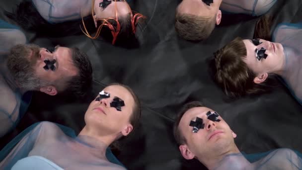 Video om liggande män och kvinnor med silvertejp på ögonen — Stockvideo
