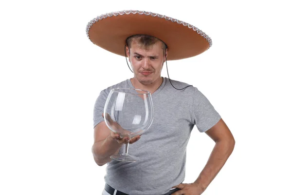 Imagen de un joven en sombrero sosteniendo un vaso grande para alcohol —  Fotos de Stock