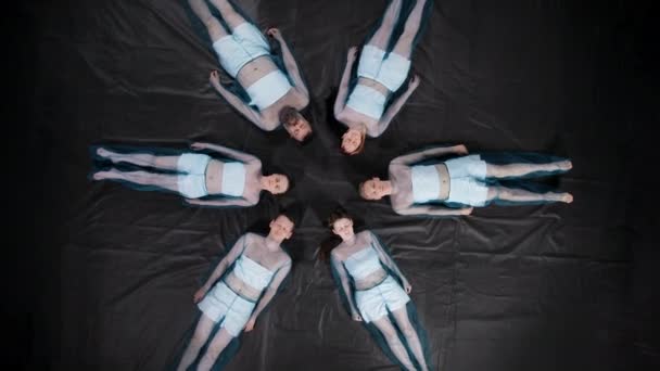 Roterende beelden van liegende mannen en vrouwen met gesloten ogen in blauwe kleren — Stockvideo