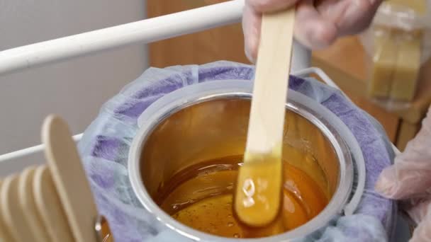 Melted brown wax and wooden stick for depilation — Stock Video