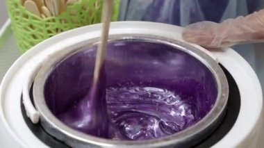 Erimiş mor mum ve tüy dökmek için ahşap çubuk.