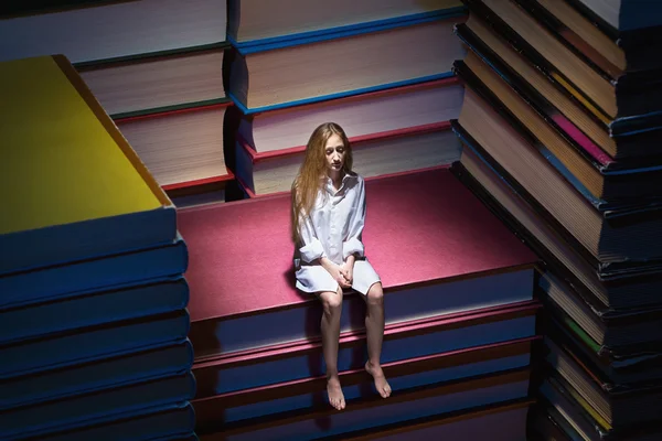 Petite jeune femme assise sur des livres — Photo