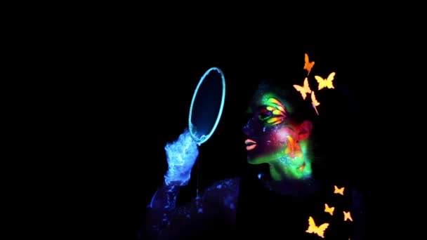 Young  woman with luminous make up blowing bubbles — Stock Video