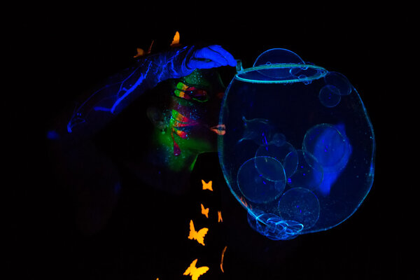 Photo of young woman blowing blue luminous bubbles