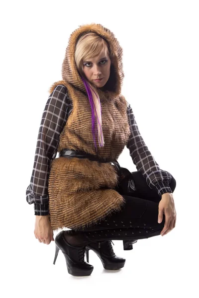 Сидящая блондинка в коричневой меховой куртке с капюшоном — стоковое фото