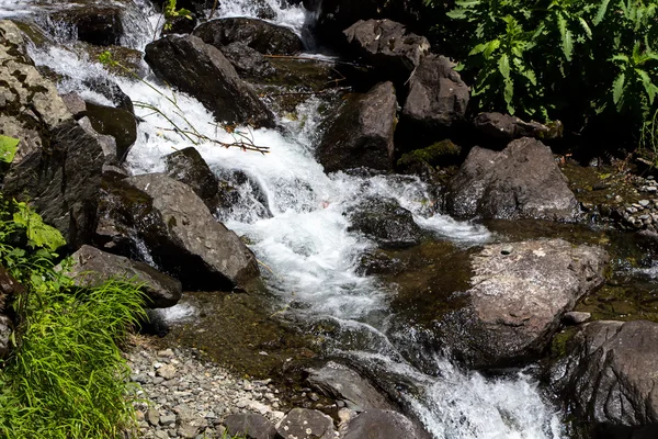 Photo of flowing water among  dark stones — Stock Photo, Image