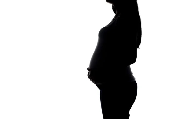 Silhouette of pregnant woman hugging belly — Stock Photo, Image