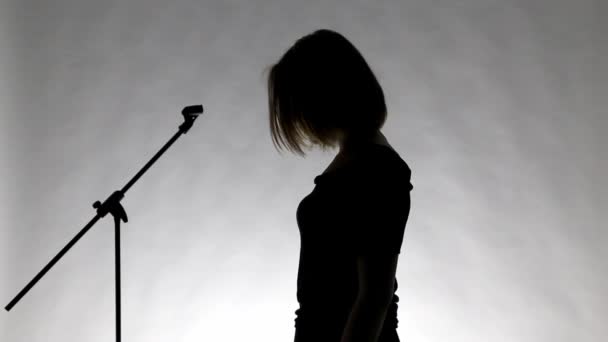 Μαύρη σιλουέτα ενός κοριτσιού με το τραγούδι microphne — Αρχείο Βίντεο