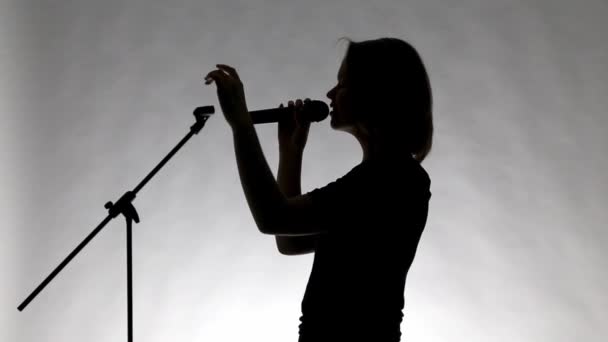 Silhouette nera di una ragazza con microfono — Video Stock