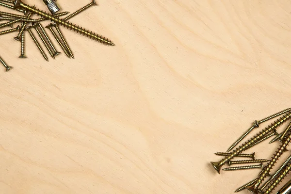 Gold screws diagonally with wood background — Stock Photo, Image