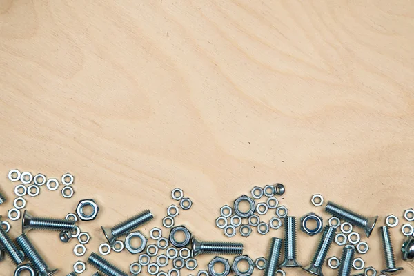 Boltas y tuercas en el fondo con fondo de madera — Foto de Stock