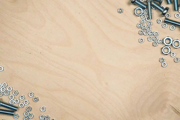 Boltas y tuercas en diagonal con fondo de madera —  Fotos de Stock