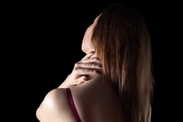 Mujer tocando cuello sobre fondo negro — Foto de Stock