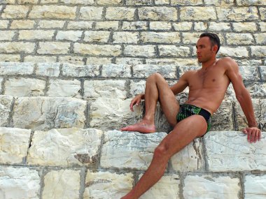 Taş duvara oturan genç adam