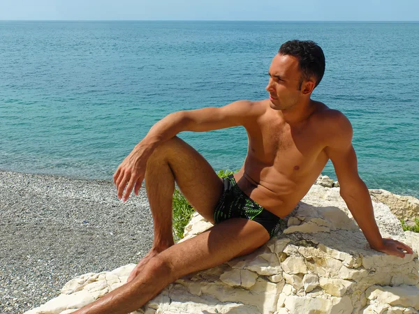 kayanın üzerinde oturan genç adam