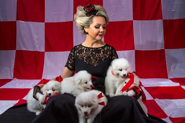 Mujer rubia en corona con cachorros esponjosos — Foto de Stock