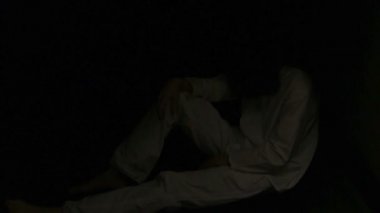 Karanlıkta bir katta oturan esmer adam