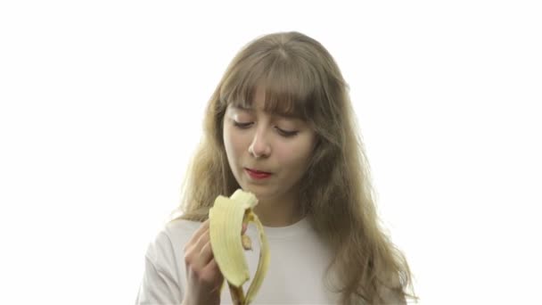 Молодая девушка откусывает спелый банан — стоковое видео