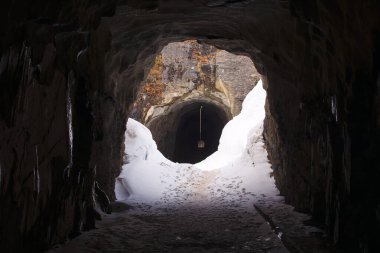 Kayaya oyulmuş, etrafı beyaz karla çevrili karanlık bir tünel. Dağın diğer tarafına geçiyorlar. Keşif, yürüyüş..