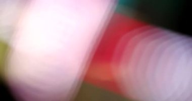 Siyah üzerine renkli ışıkların hareket etmesinin soyut arkaplanı. Parlak ışıkların renkleri değişiyor.