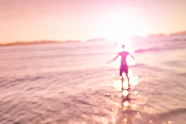 Verschwommene defokussierte Silhouette des Menschen, der am Meer mit geneigtem Horizont steht - Konzept der Freiheit und des Fernwehs mit einer Person im Wasser am Strand von Las Cabanas in El Nido Palawan - Rosenquarz gefilterter Look — Stockfoto