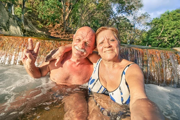 Senior happy couple taking selfie at Maquinit Hot Spring in Coron - Relax concept to Philippines wonders and active elderly traveling around the world - Warm afternoon color tones with tilted horizon — ストック写真