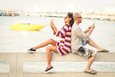 Yolcuları çift ilgisizlik an cep telefonlarıyla Pattaya Beach - apati ve bağımlılık kavramı ile sıkılmış insanlar akıllı telefonlar - yumuşak kullanarak filtre ile hafif eğik ufuk desaturated