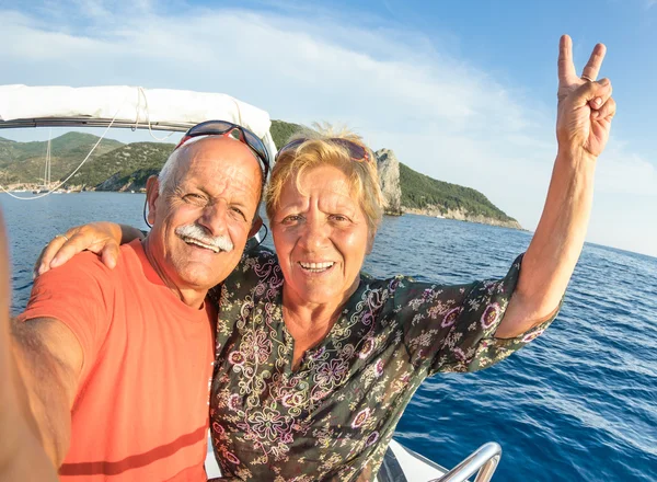 Pareja mayor aventurera tomando selfie en Giglio Island en lancha rápida de lujo - Concepto activo de estilo de vida de viajes de ancianos en el momento de la gira feliz - Personas jubiladas en todo el mundo - Tonos cálidos de color de la tarde —  Fotos de Stock