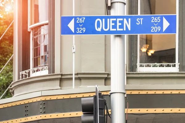 Street sign of Queen Street in Auckland - Urban concept and road direction in the biggest city of New Zealand - Australasian world famous destination with warm filter and enhanced sunshine halo — Stock Photo, Image