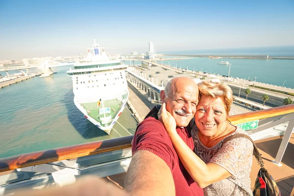 Senior happy couple taking selfie on ship at Barcelona harbour background - Mediterranean cruise travel tour - Active elderly concept with retired people around the world - Warm afternoon color tones — Stock Photo, Image