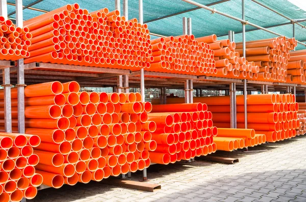 Stapel orangefarbener PVC-Wasserleitungen im verlassenen Industriegebiet - Baukonzept mit Kunststoffstapel auf Baustelle — Stockfoto