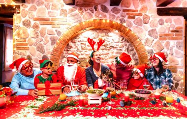 Noel Baba kıyafetli çok nesilli aile Noel Baba festivalinin ev partisinde eğleniyor - kış tatili aile ve çocuklarla birlikte yemek yeme kavramı - Ren geyiği şapkalı merkezi kadına odaklan