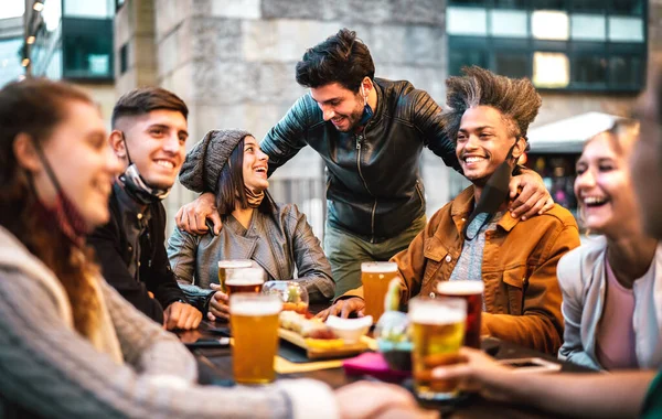 オープンフェイスマスクでビールを飲む若者たち 一緒にビールバーの外で幸せな時間に話を楽しんでミレニアルと新しい通常のライフスタイルの概念 中心的な人々に焦点を当てた暖かいフィルター — ストック写真