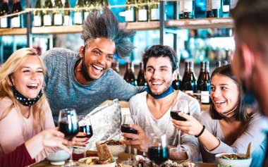 Füzyon bar restoranında kırmızı şarap içen insanlar, yemek yaşam tarzı ve mutlu arkadaşlarla moda lokantasında eğlenen yeni normal konsept soldaki Afroamerikalı adamın yüzüne seçici bir şekilde odaklanıyorlar.