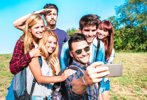 People group taking selfie at trekking excursion - Happy friendship and freedom concept with young millenial friends having fun together at camping experience - Bright vivid filter