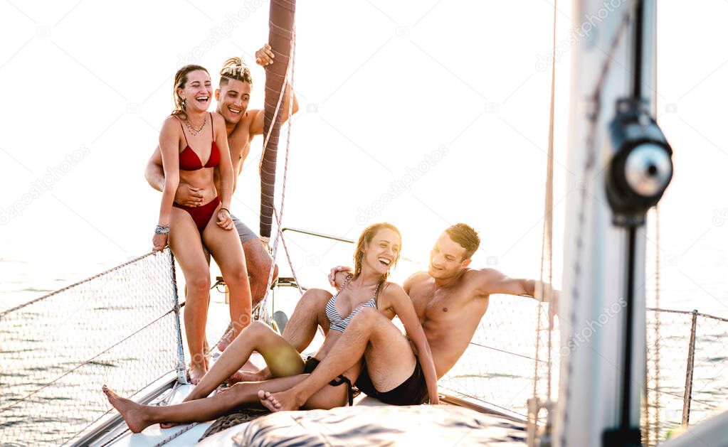 Young couple friends chilling on sailboat at sea ocean trip - Guys and girls having summer fun together at sail boat party day - Luxury concept on warm bright filter