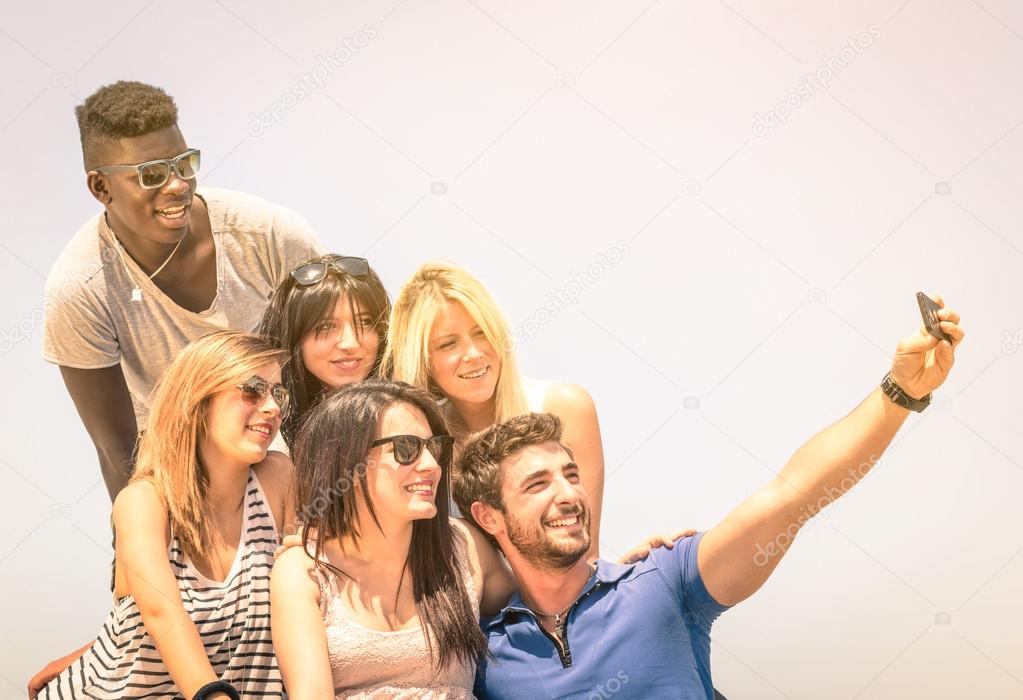 Group of multiracial happy friends taking a selfie outdoors - International concept of happiness and multi ethnic friendship all together against racism for peace and fun - Vintage filtered look