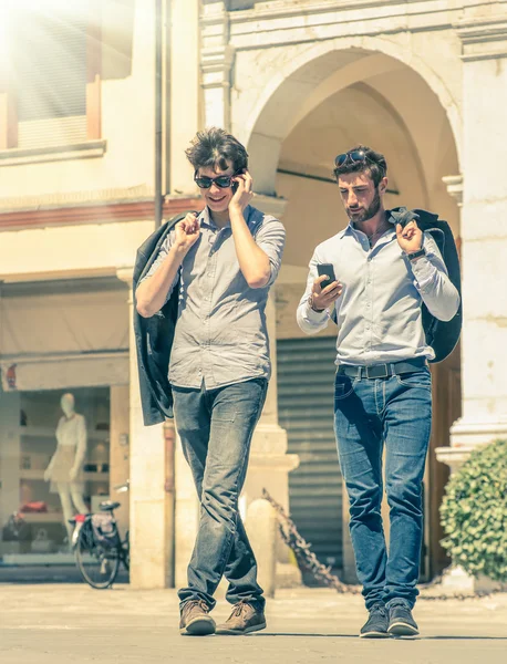 Jovens homens de negócios na praça principal da cidade com smartphone tendo uma pausa depois de um dia útil mensagens SMS sms - Conceito moderno de vida urbana e metropolitana em um olhar filtrado vintage — Fotografia de Stock