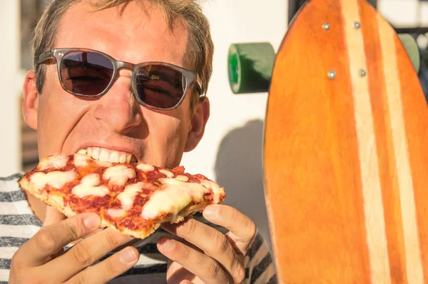 Giovane bel ragazzo hipster mangiare una fetta di pizza margherita - Stile di vita vintage giovane durante l'azione longboard e portare via il cibo — Foto Stock