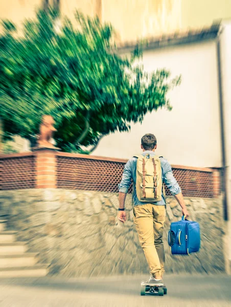 Young hipster man moving forward with his longboard holding his trolley backpack - Modern concept of freedom and alternative lifestyle - Cheap travel backpacking around the world — Stock Photo, Image