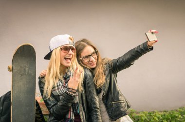 Hippi kız arkadaşlarım an modern smartphone ile eternalizing bir selfie - dostluk ve yeni trendler ve teknoloji ile eğlenceli kavramı - kentsel şehir bağlamda alarak